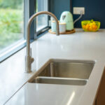 stainless steel sink, on a white stone work top